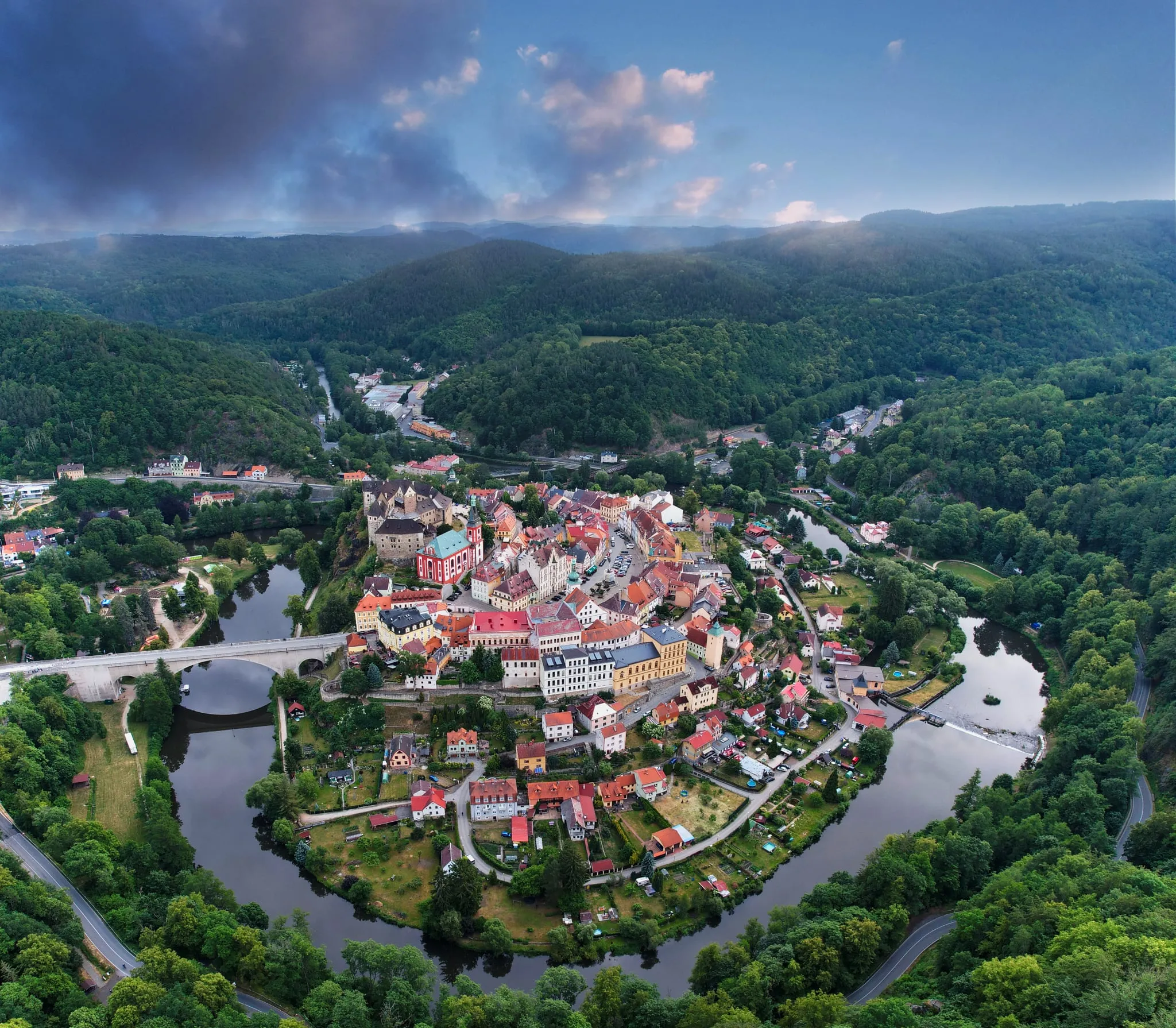 The historic town of Loket in the bend of a river, wooded hills all around