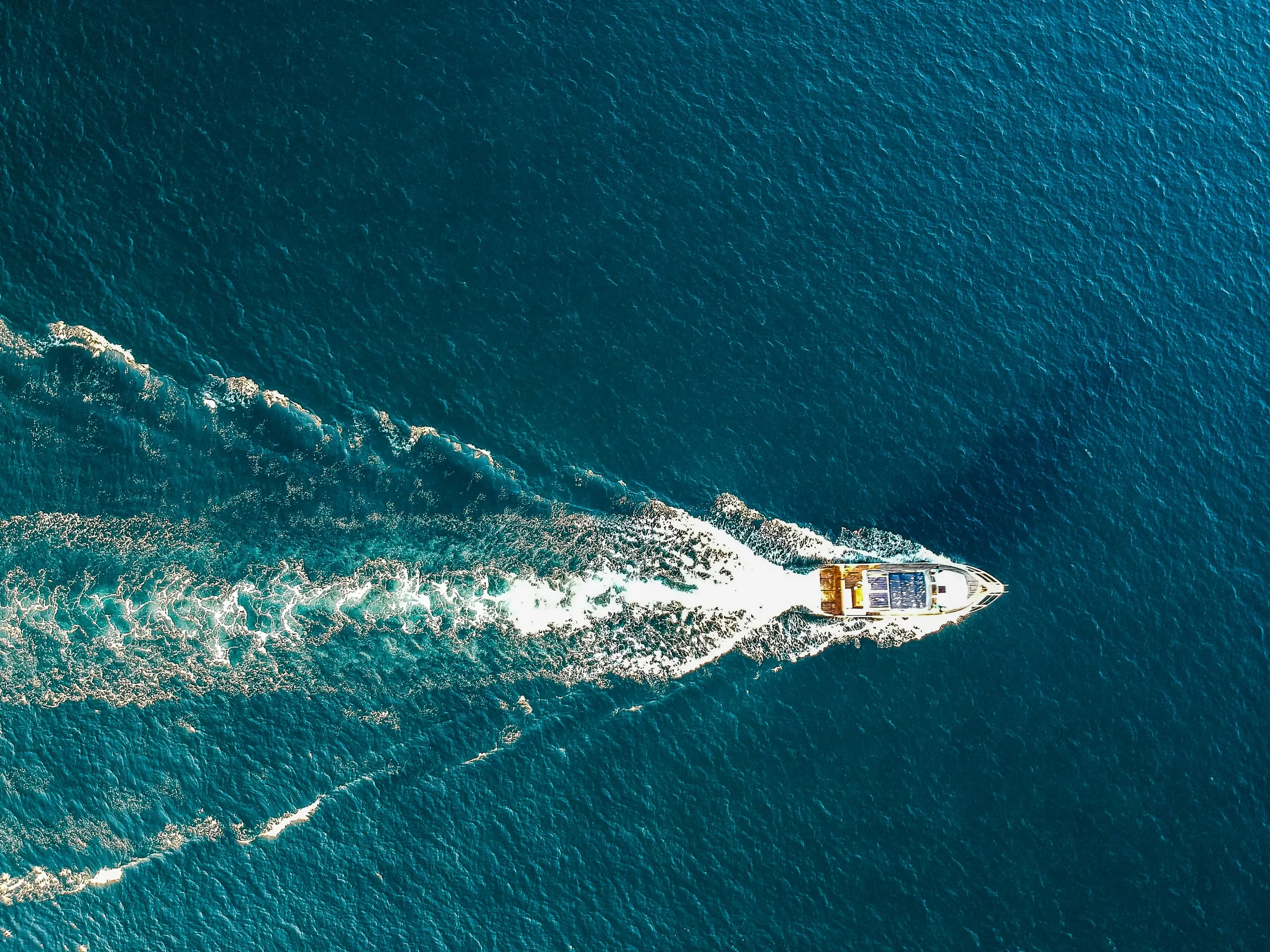 A motorboat with a white wake on the sea off the coast of Istria, from straight above