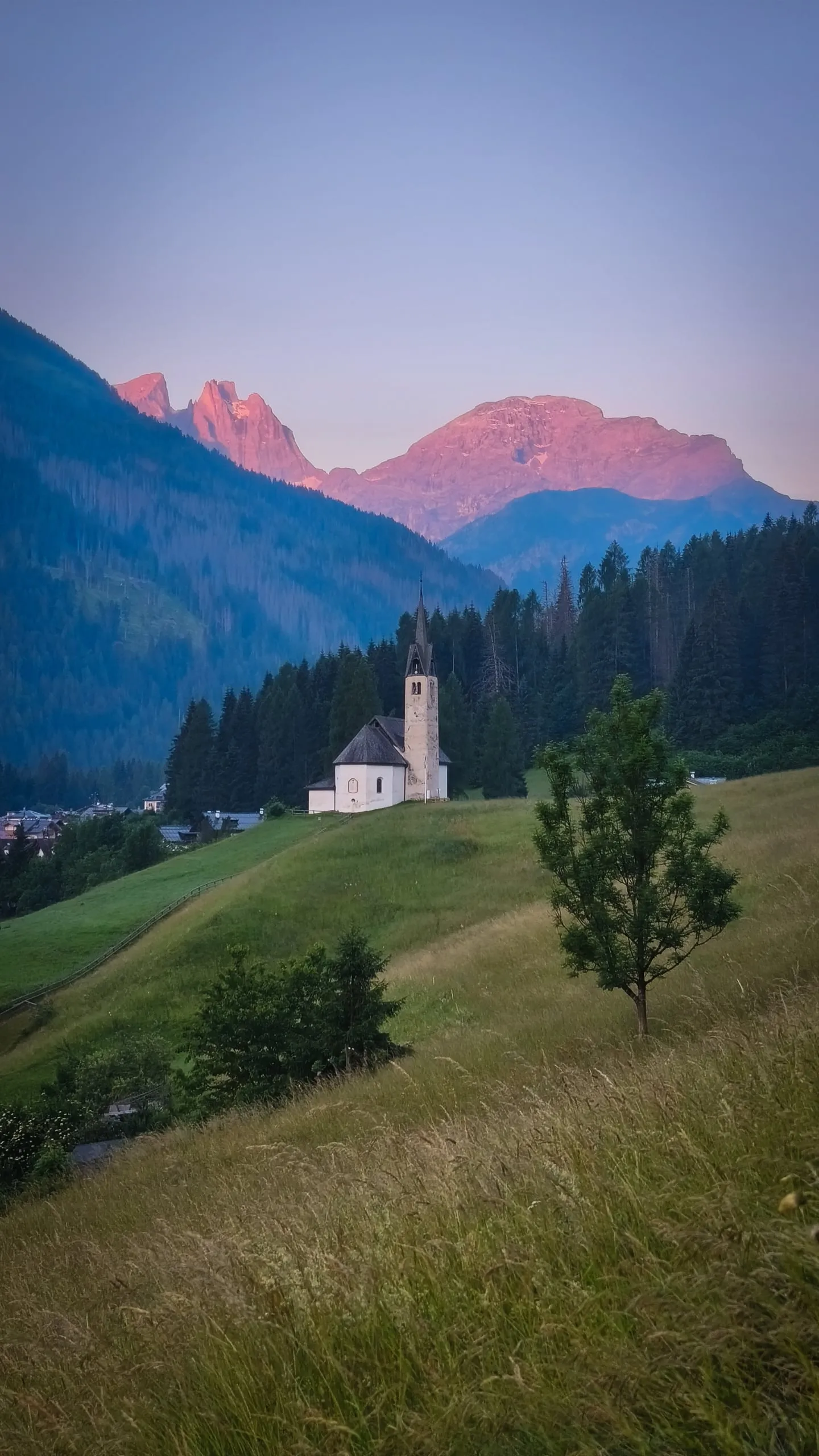 A church on a hill in Italy, mountains in alpenglow behind it