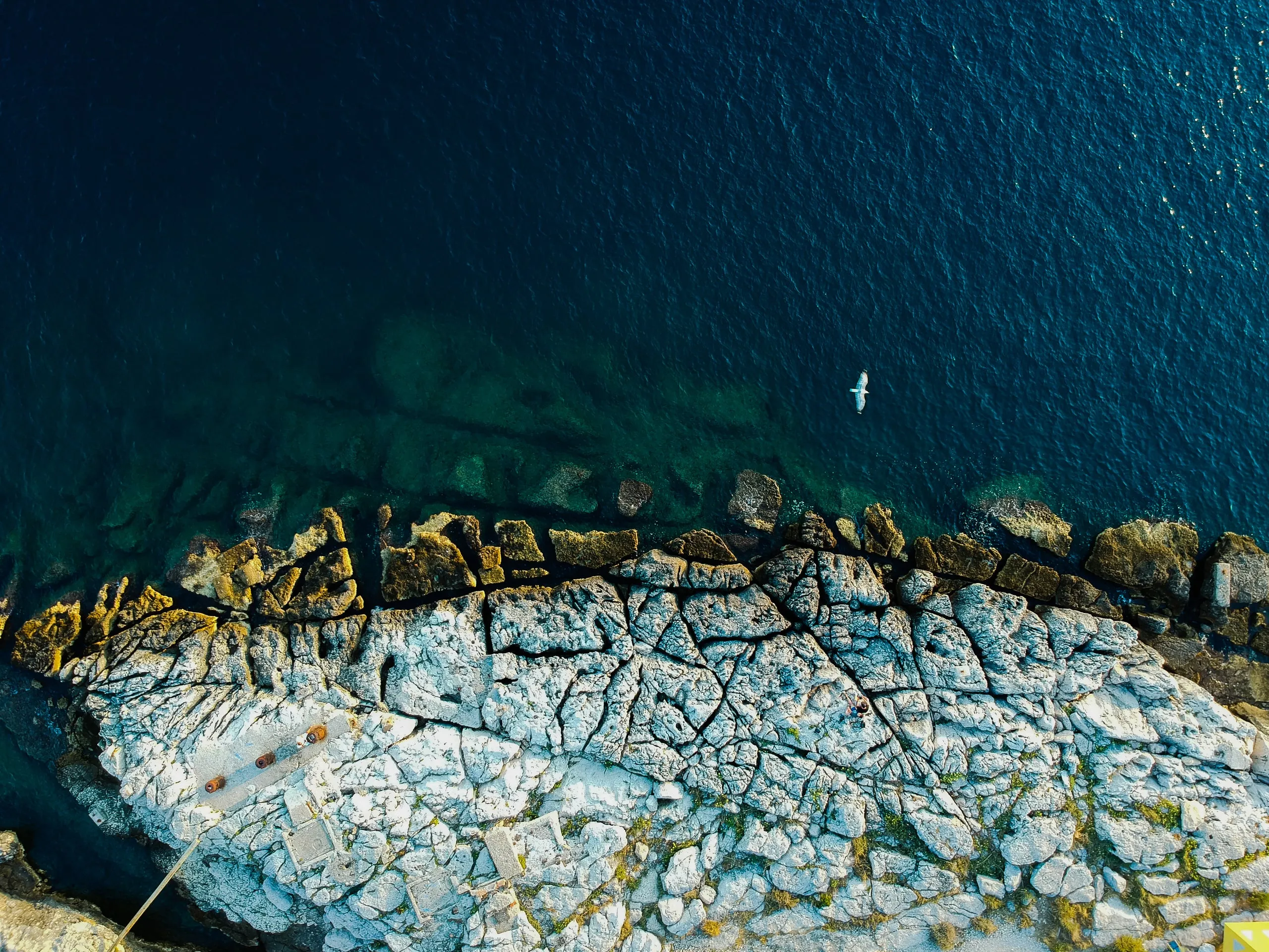Cracked pale rocks on the coast near Pula and dark sea, from straight above