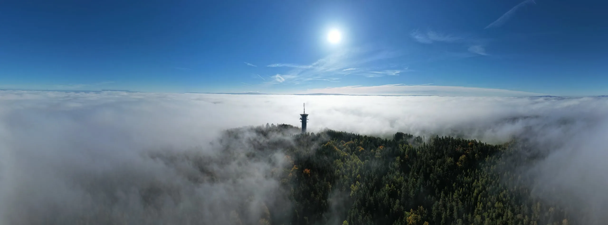 The transmitter tower on Zelená hora stands out of a sea of fog, the sun above it