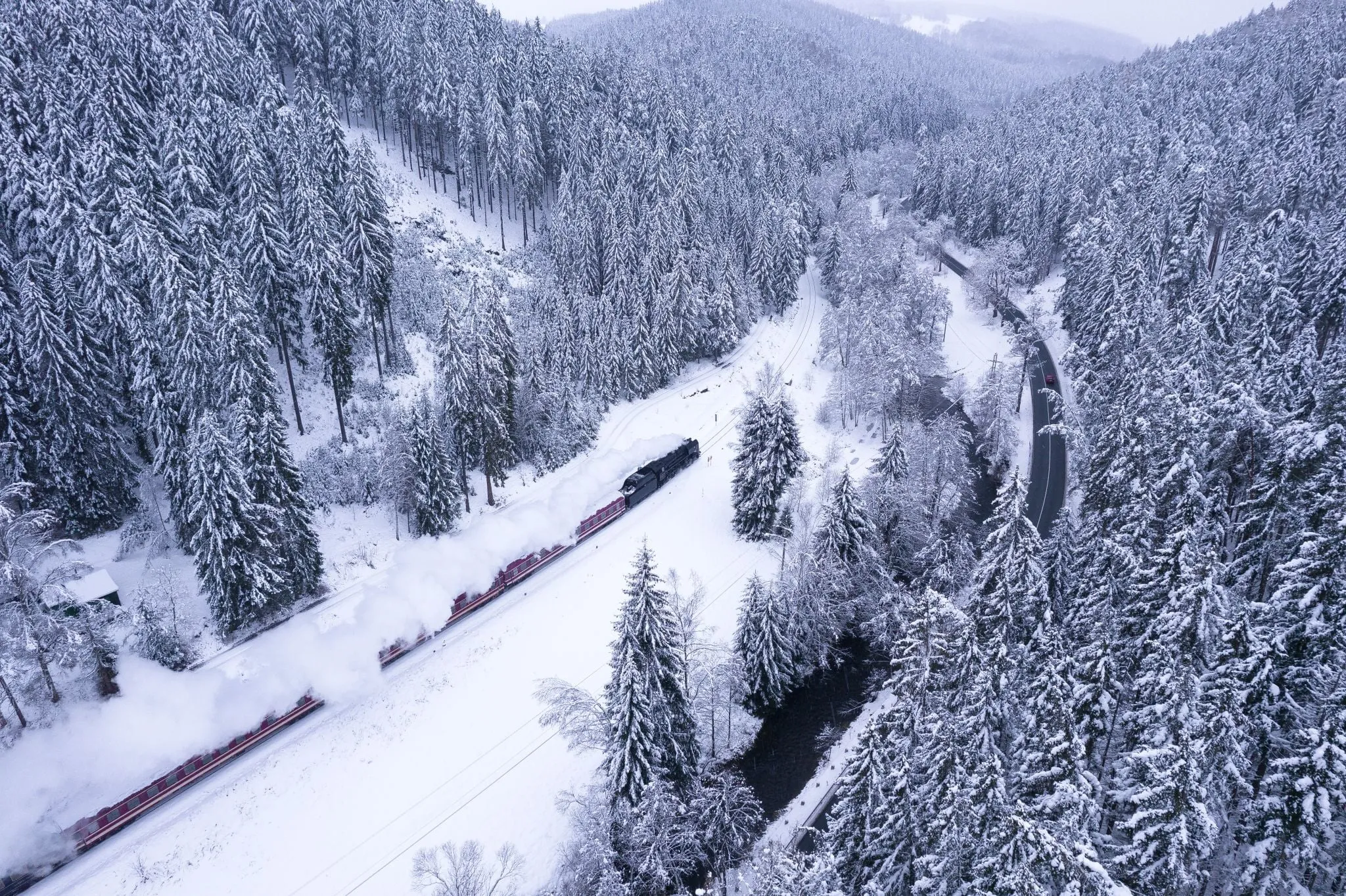The steam locomotive of the St Nicholas train with red carriages on the line to Kraslice through snowy forest