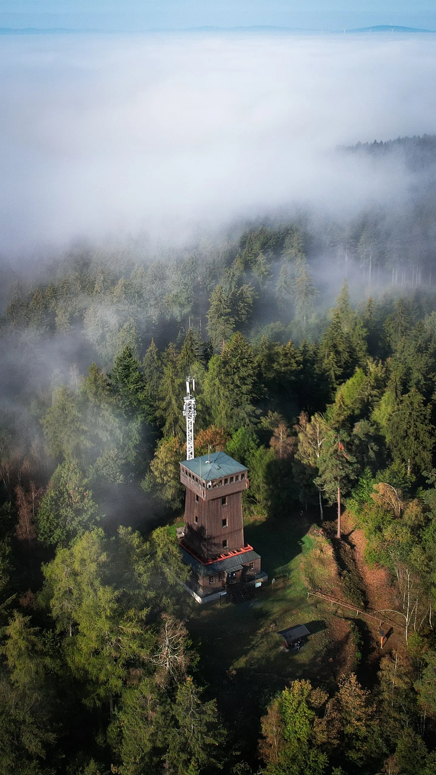 The Kapellenberg lookout tower on a wooded hill with fog rolling around it