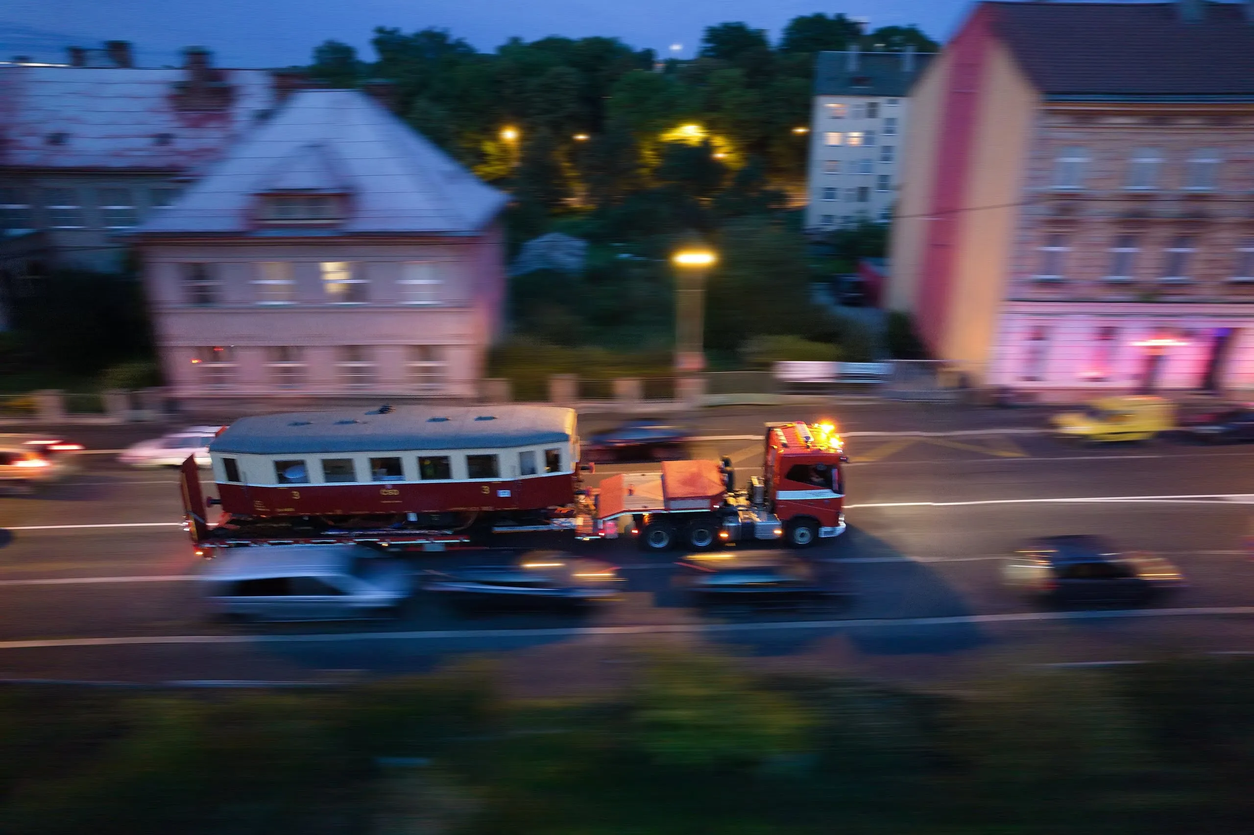 The railway fire brigade moving a railcar on a low-loader through a street in the evening