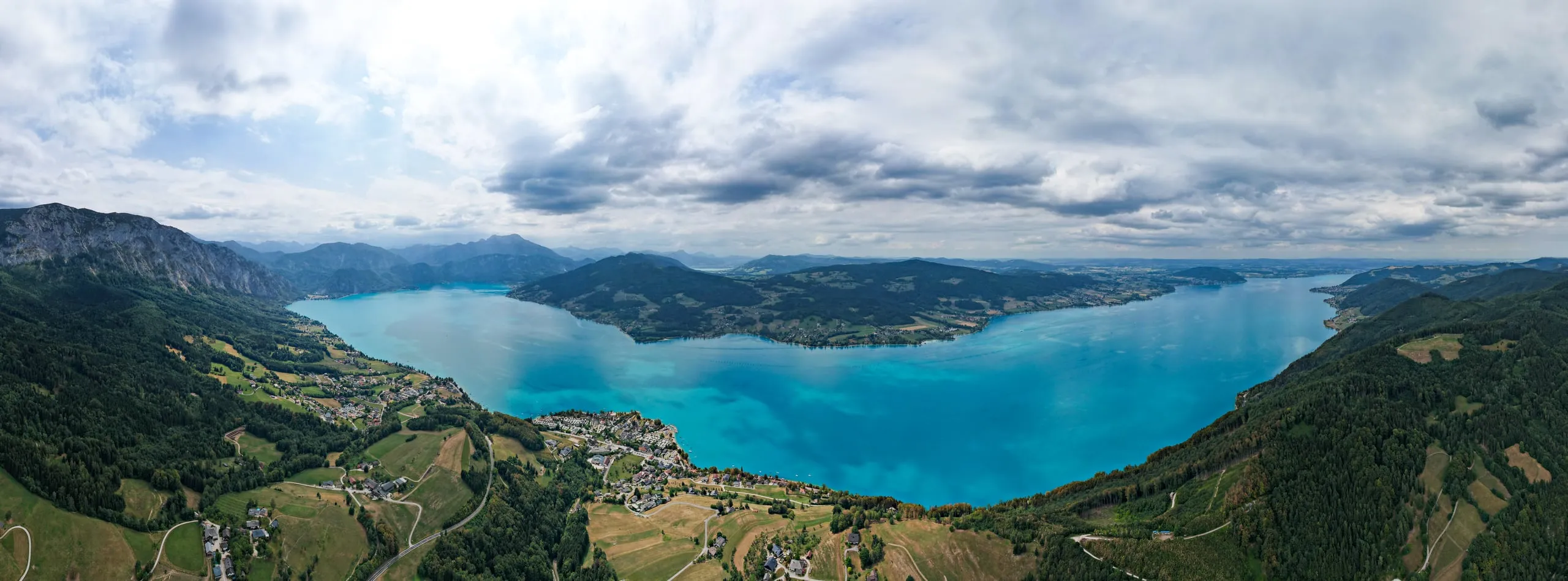 Panorama of the turquoise Attersee between wooded slopes