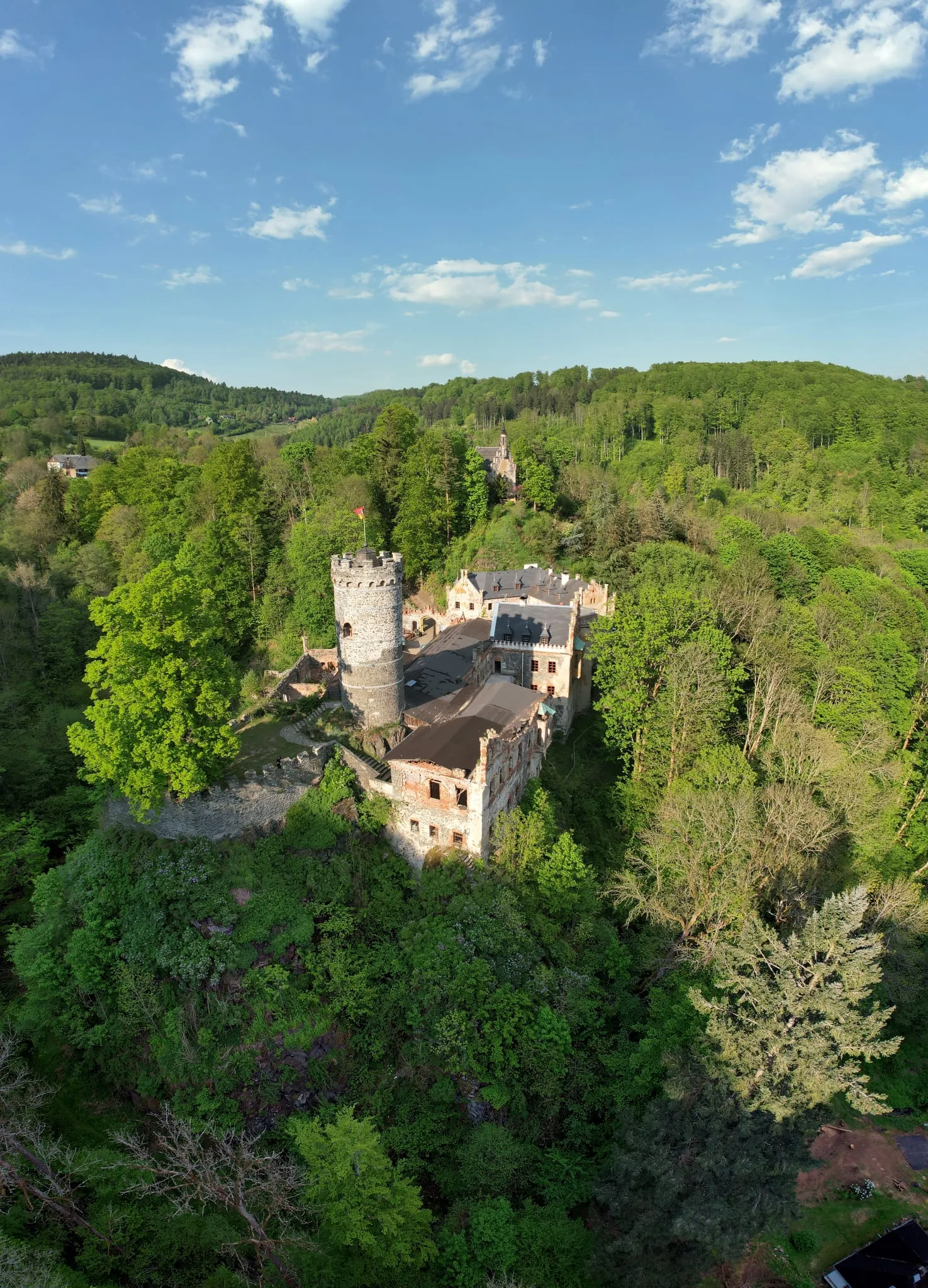 Horní hrad with its round tower in the middle of a spring forest in the Ore Mountains