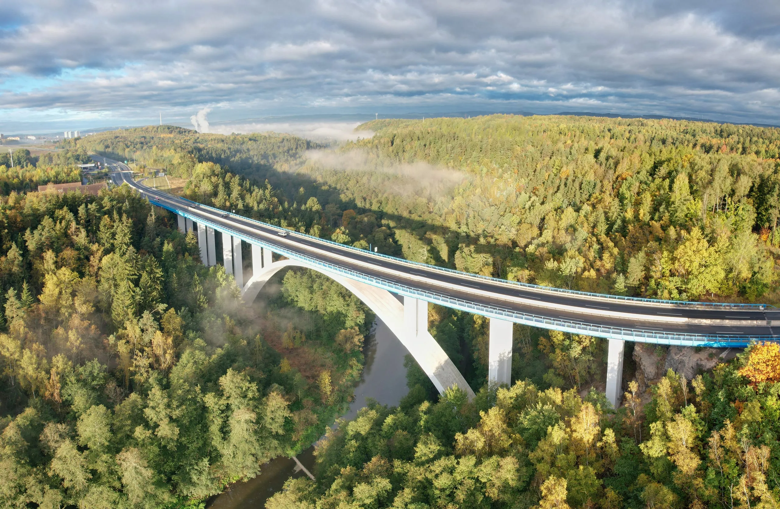 A motorway bridge across a wooded valley in autumn
