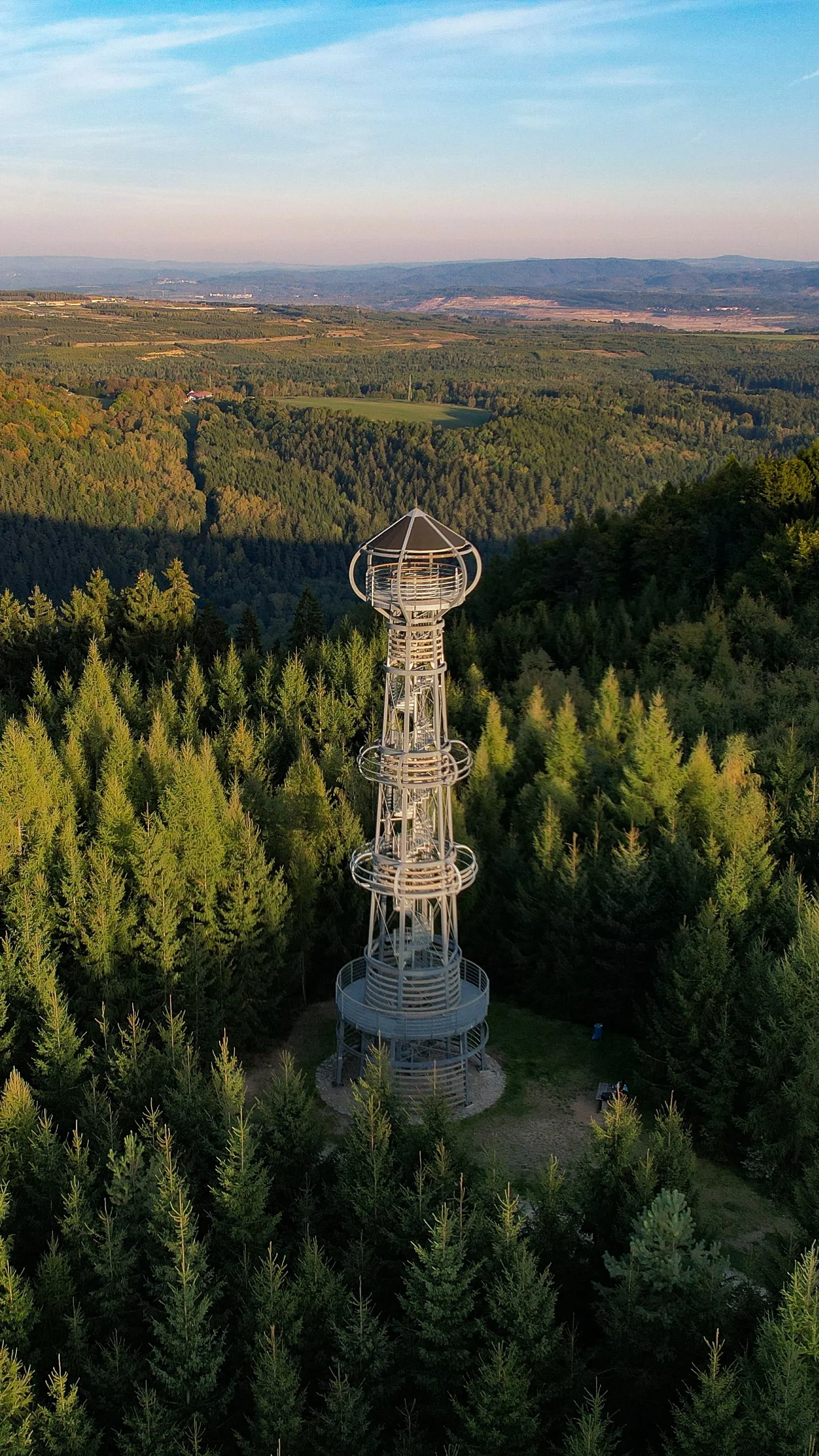 The steel Cibulka lookout tower among spruces in the Ore Mountains in early evening light