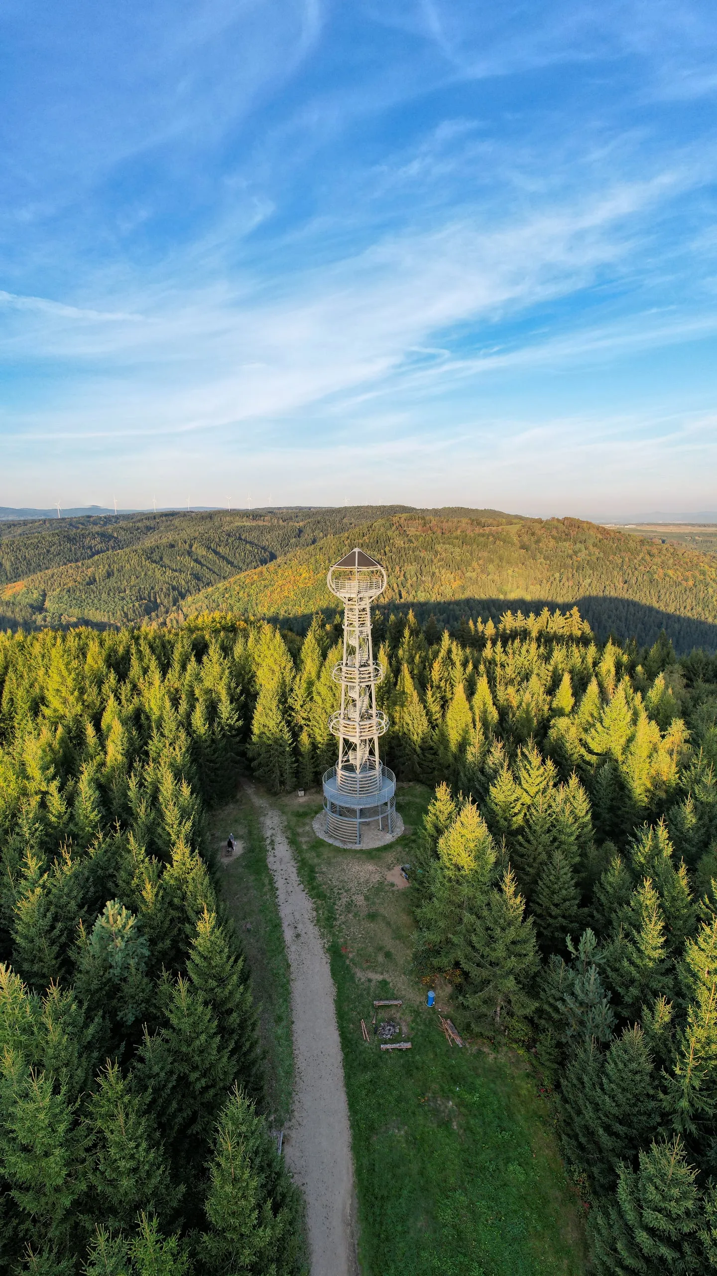 The steel Krudum lookout tower by a forest track, wooded ridges in the background