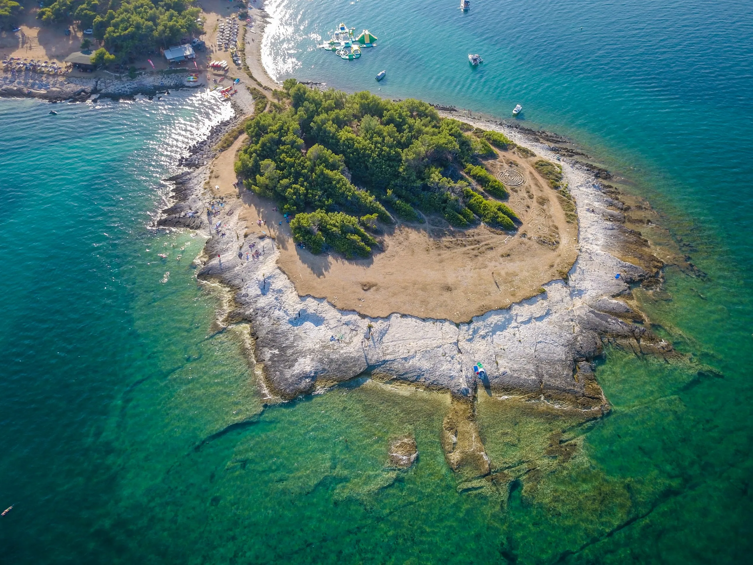 A small island with trees and a rocky shore in turquoise sea off Cape Kamenjak in Istria