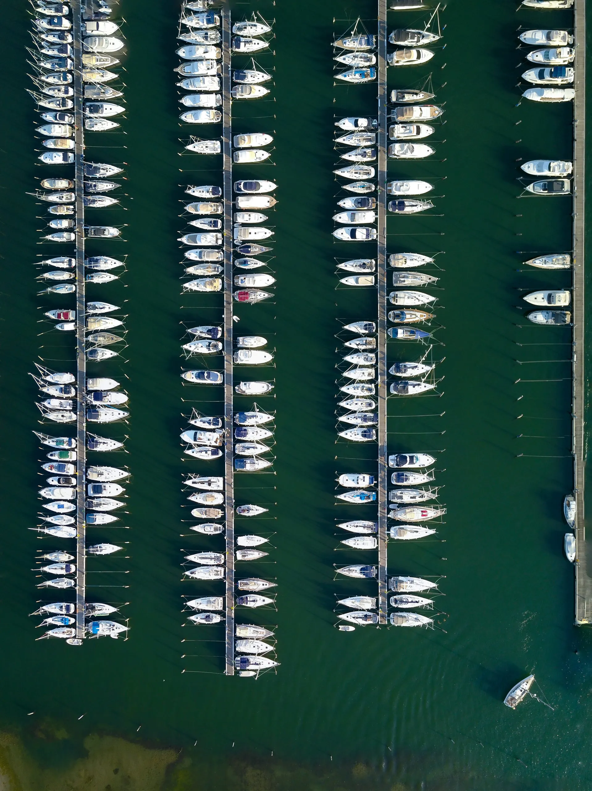 Rows of yachts at the jetties of a marina, from straight above