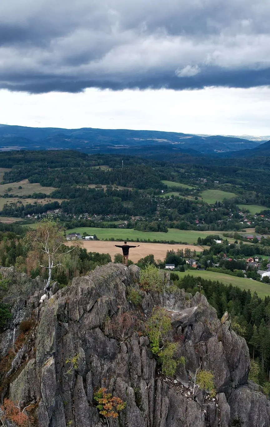 A figure on a rock outcrop above the landscape, taken from a drone